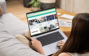 Woman sat on a sofa, with a laptop on her knees, selecting an online training course. 