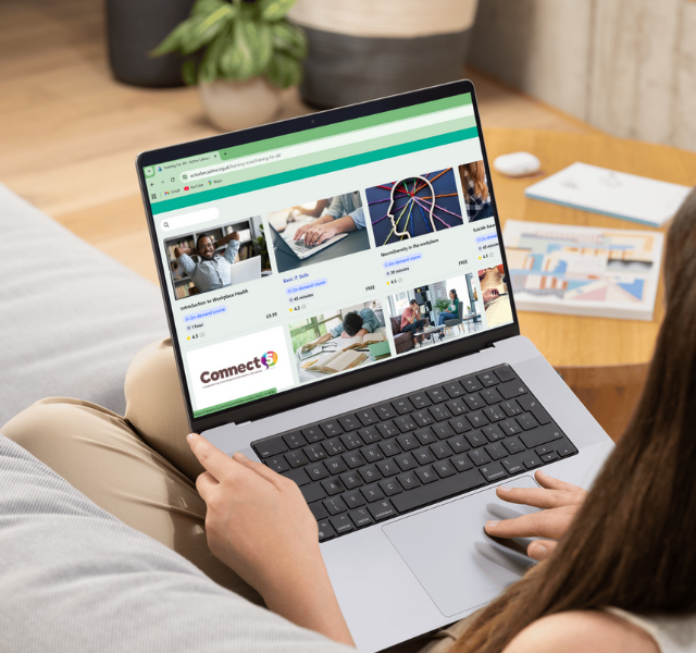 Woman sat on a sofa, with a laptop on her knees, selecting an online training course.
